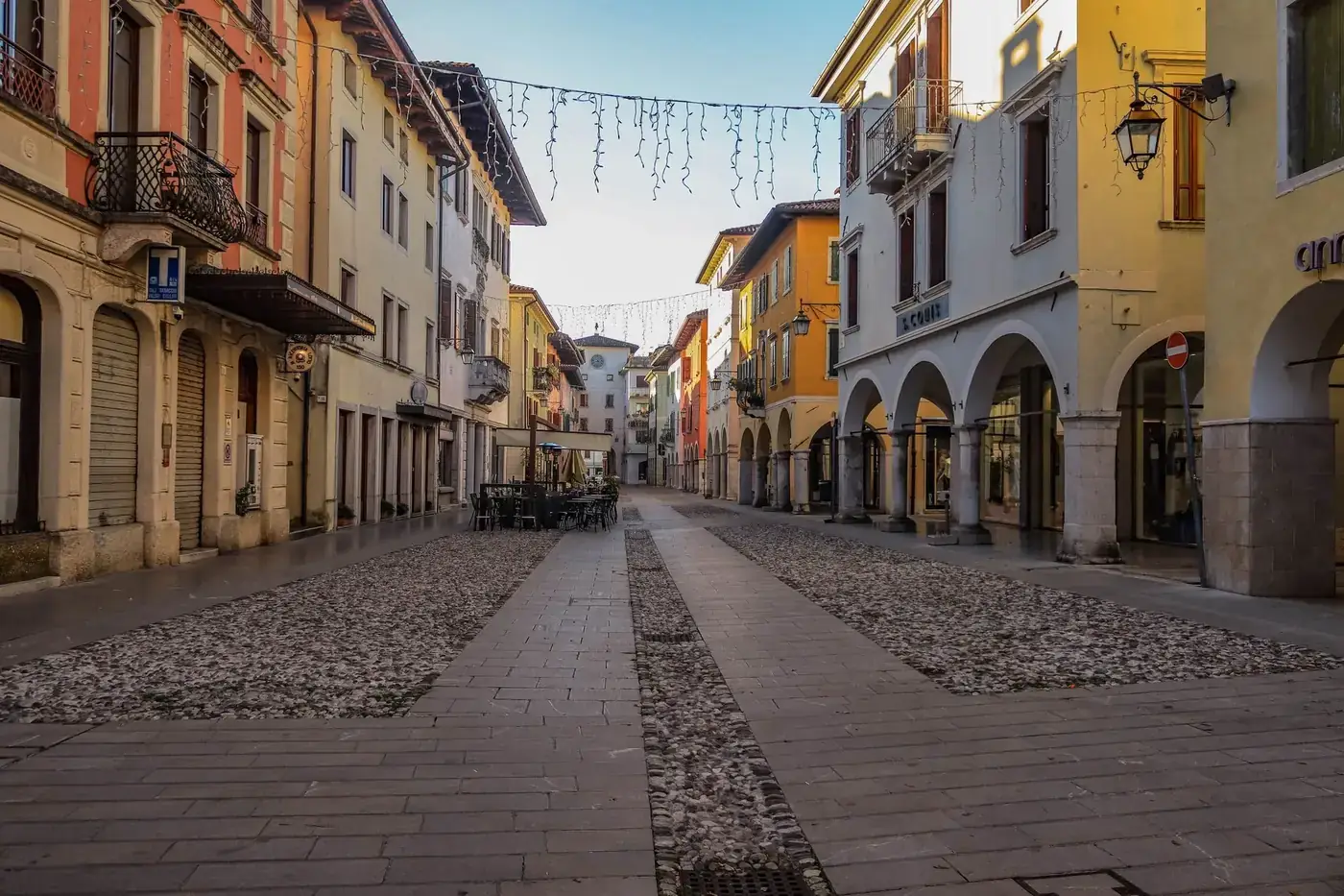 A serene, picturesque European street with colorful buildings and cobblestone pavement during the day.