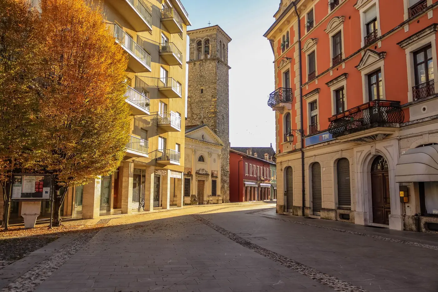 Charming European street scene with colorful autumn trees and historic buildings under a clear sky.