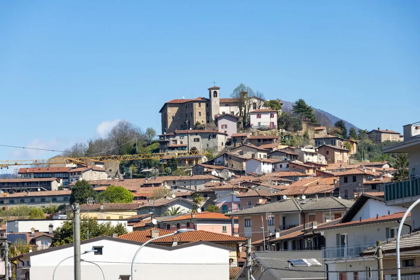 Charming hilltop view of Capriolo village in Lombardia, Italy with rustic architecture and blue sky backdrop.