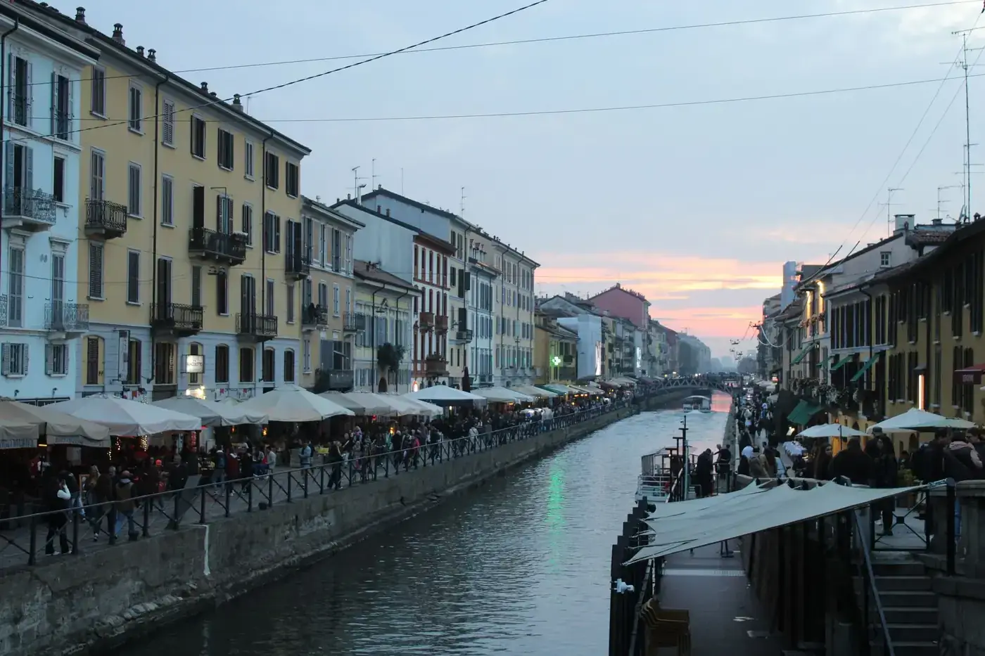 Scenic evening view of Naviglio Grande canal in Milan with vibrant street life.