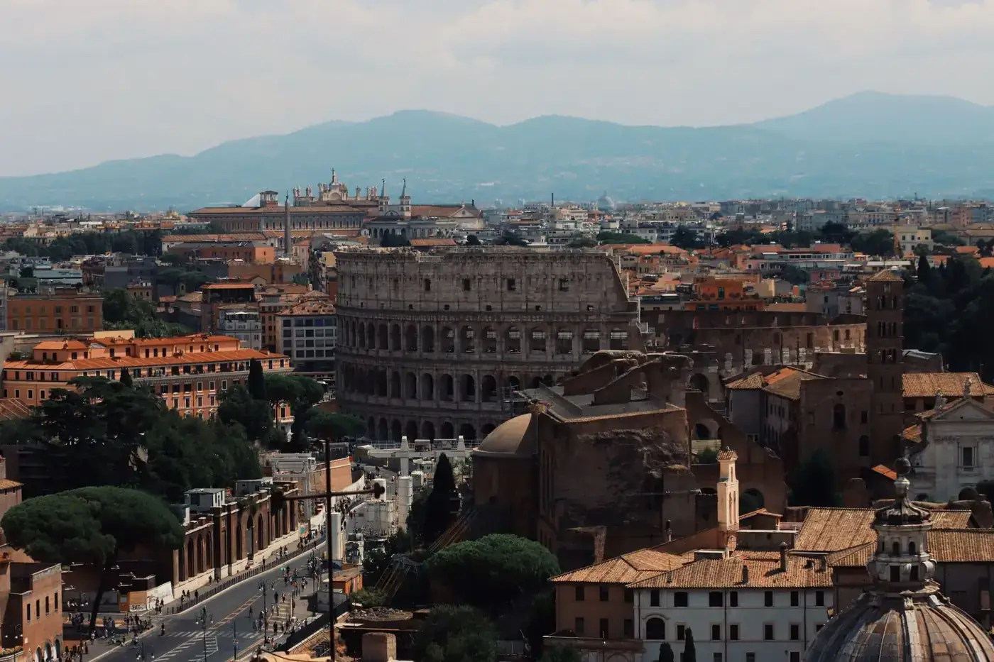 Drone shot of the iconic Colosseum and surrounding cityscape in Rome, Italy.