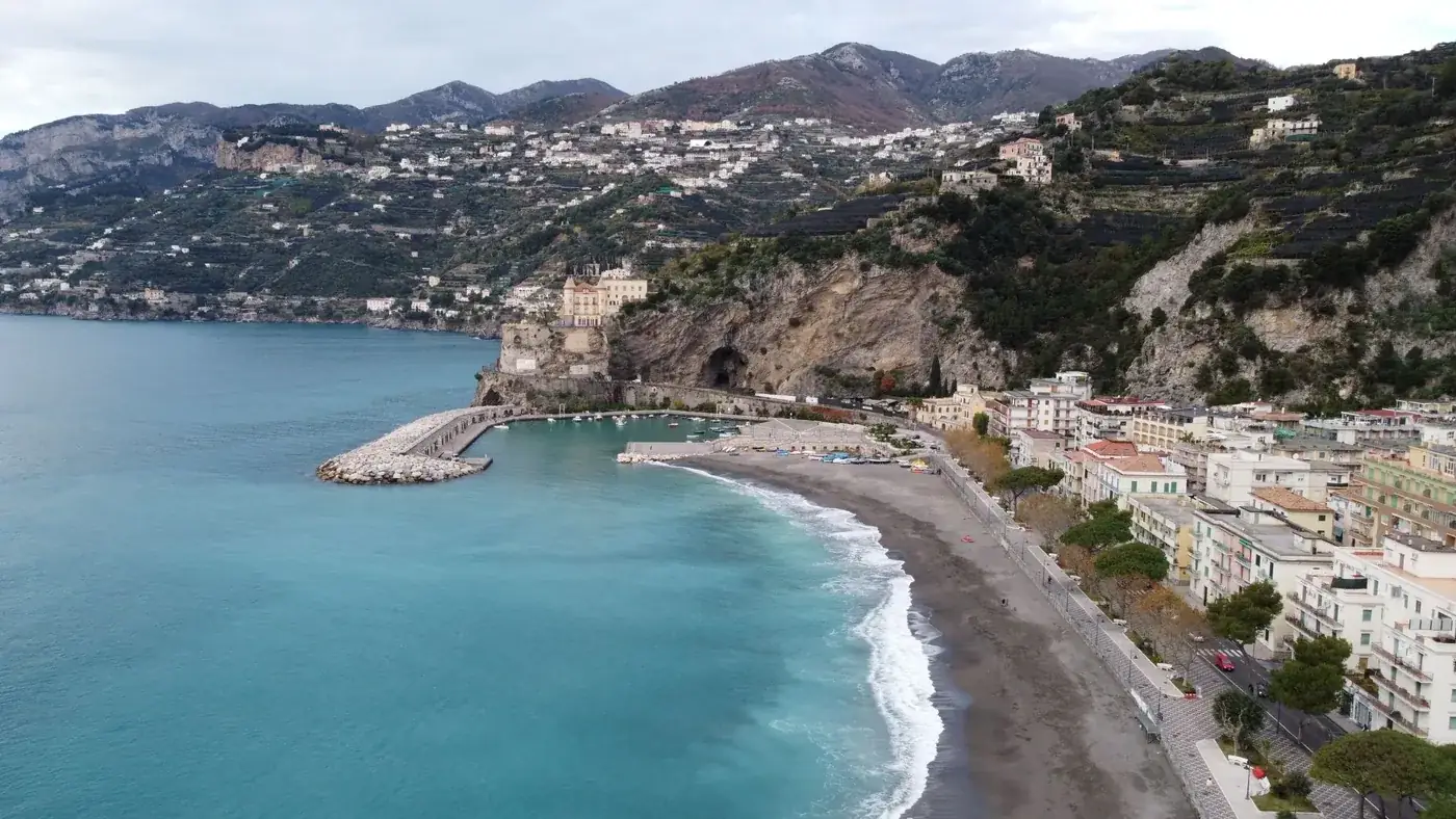 Aerial shot of Sorrento's coastline in Italy with a picturesque beach, bay, and cliffs.