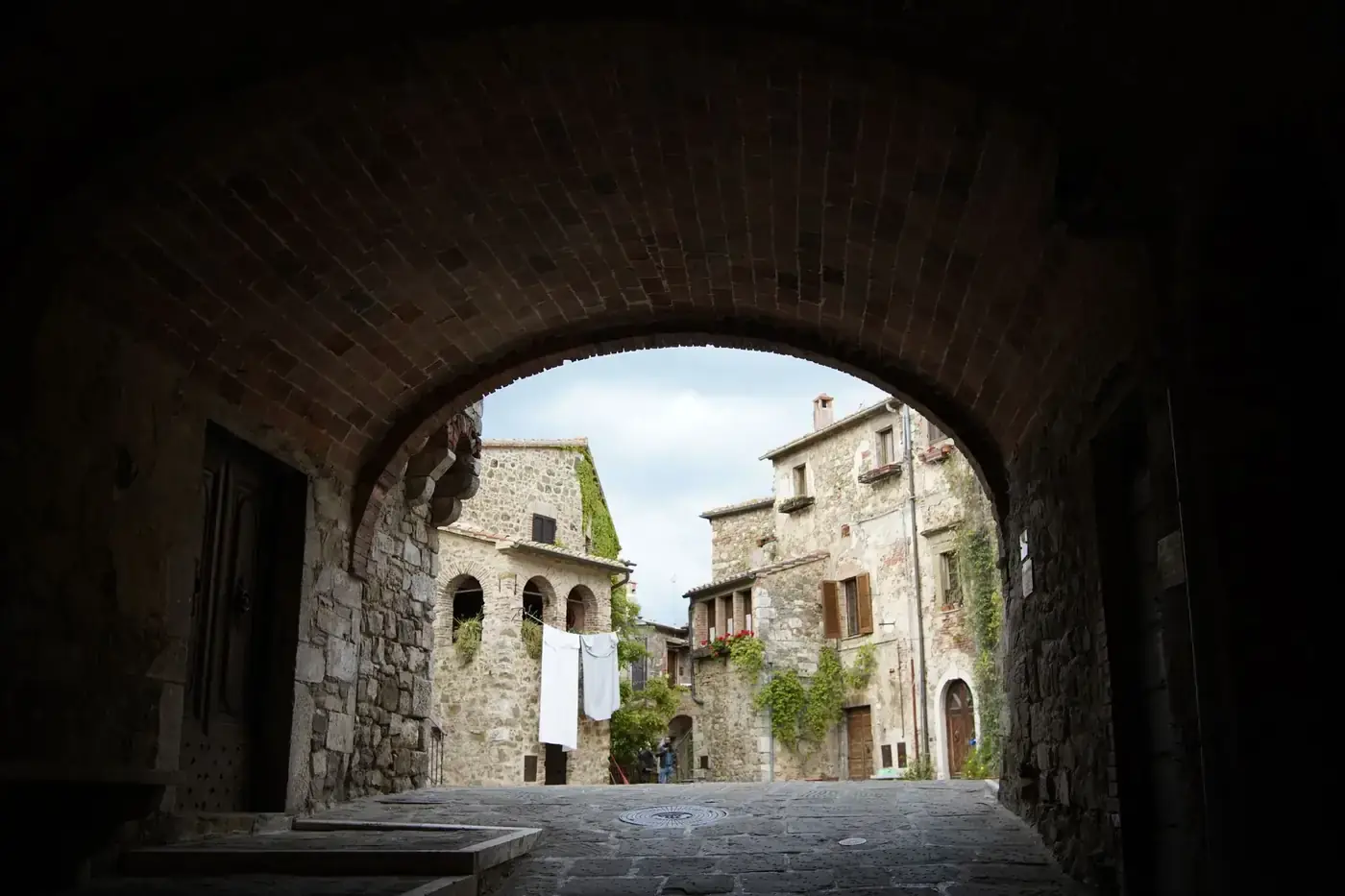 Charming stone buildings seen through an ancient arch in Montemerano, Tuscany.
