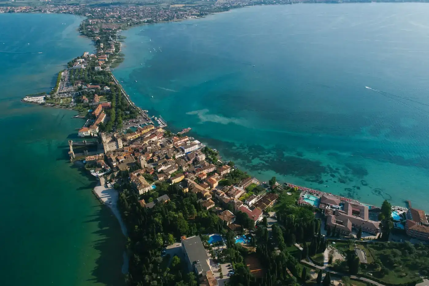 Scenic aerial shot of a coastal town with turquoise sea and lush greenery.