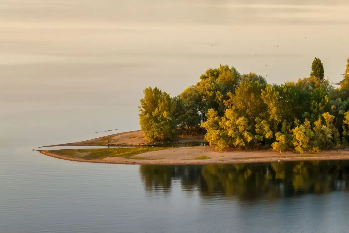 Scenic aerial view of a tranquil island with lush autumn foliage reflecting on calm waters.