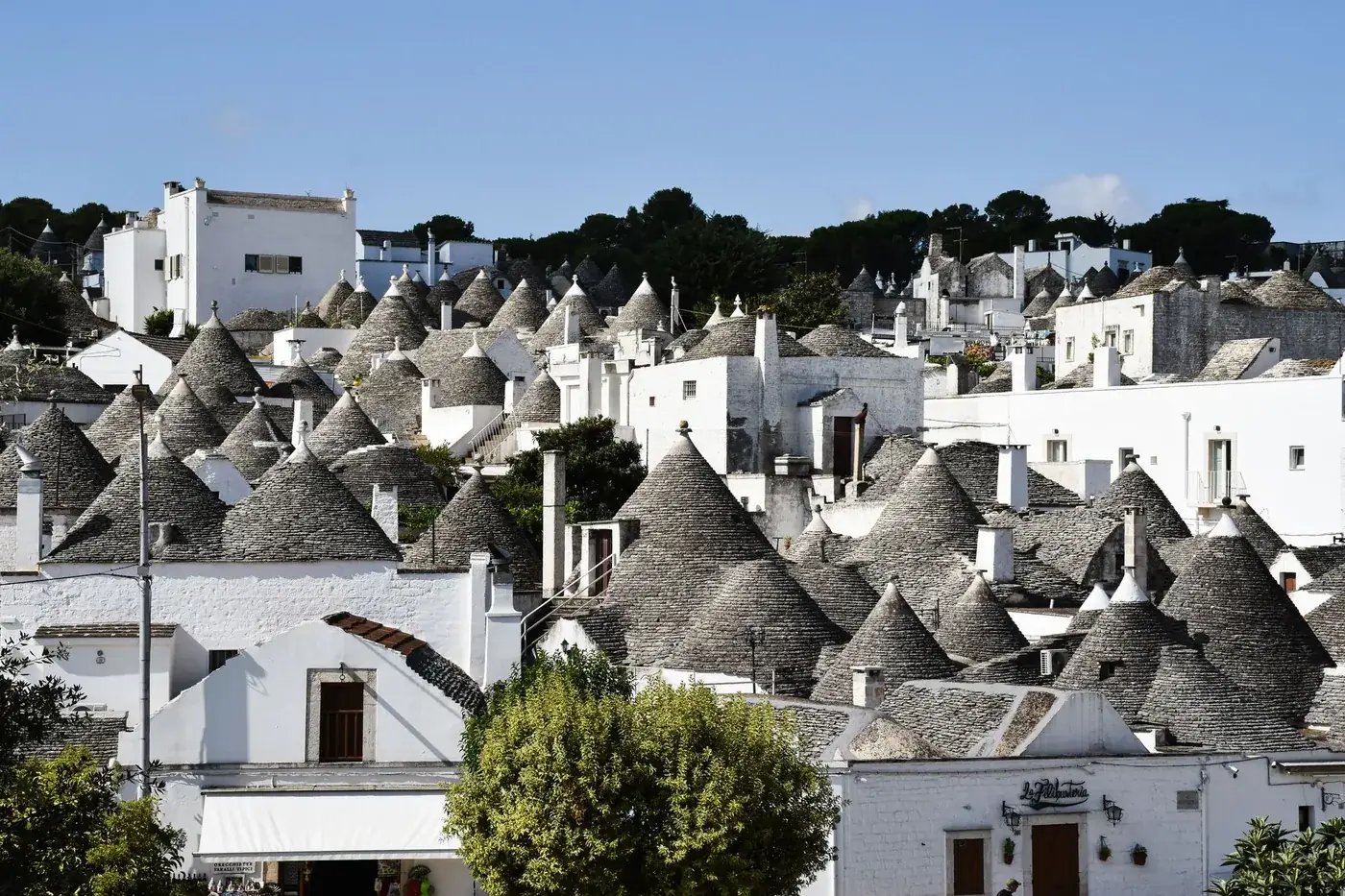 Explore the unique architecture of trulli houses in Apulia, Italy, under a clear blue sky.
