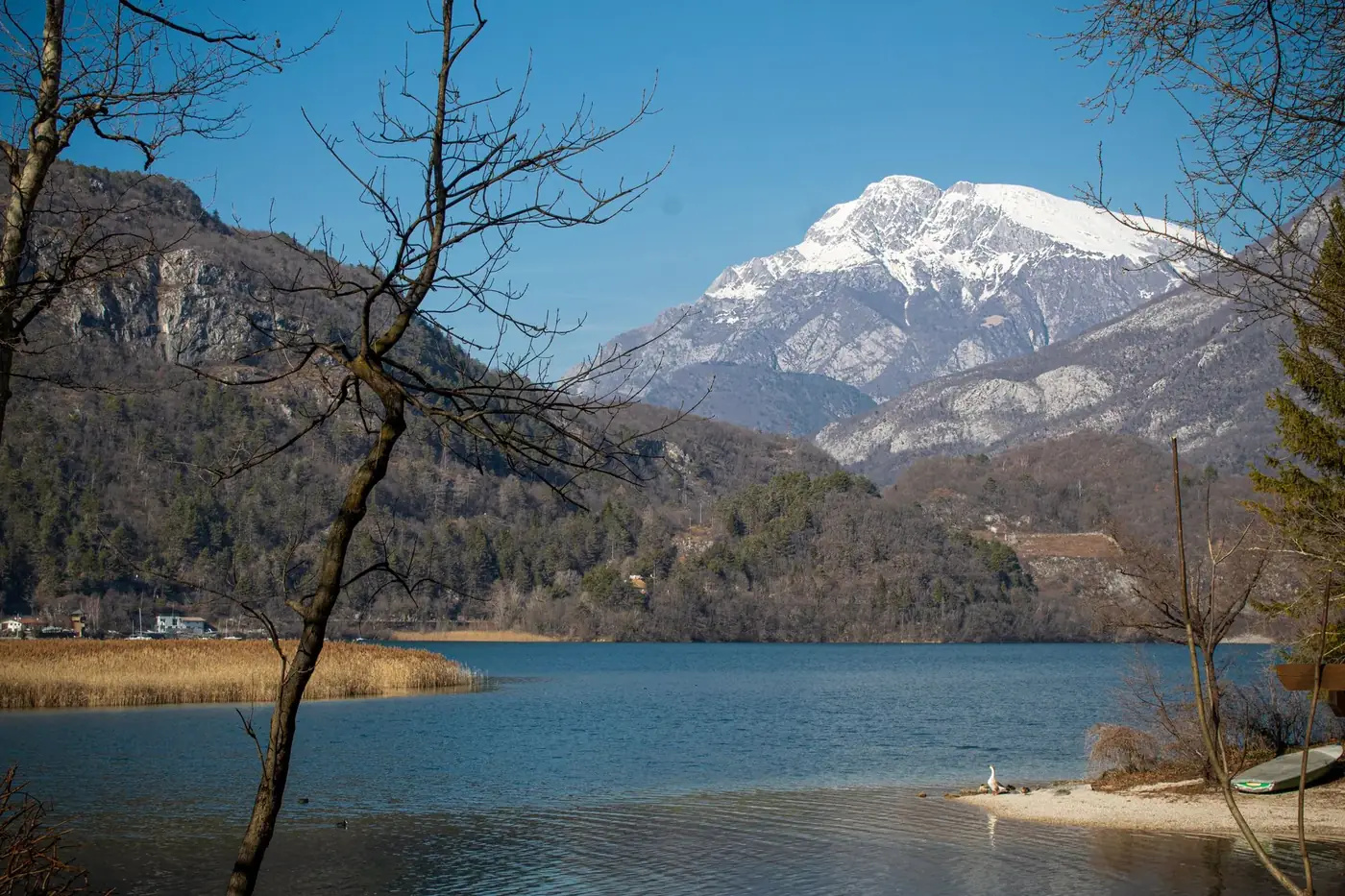 Breathtaking winter landscape of Lago di Cavazzo with snowy mountains in Friuli-Venezia Giulia, Italy.