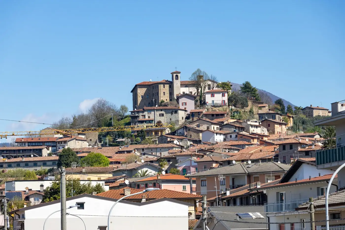 Charming hilltop view of Capriolo village in Lombardia, Italy with rustic architecture and blue sky backdrop.