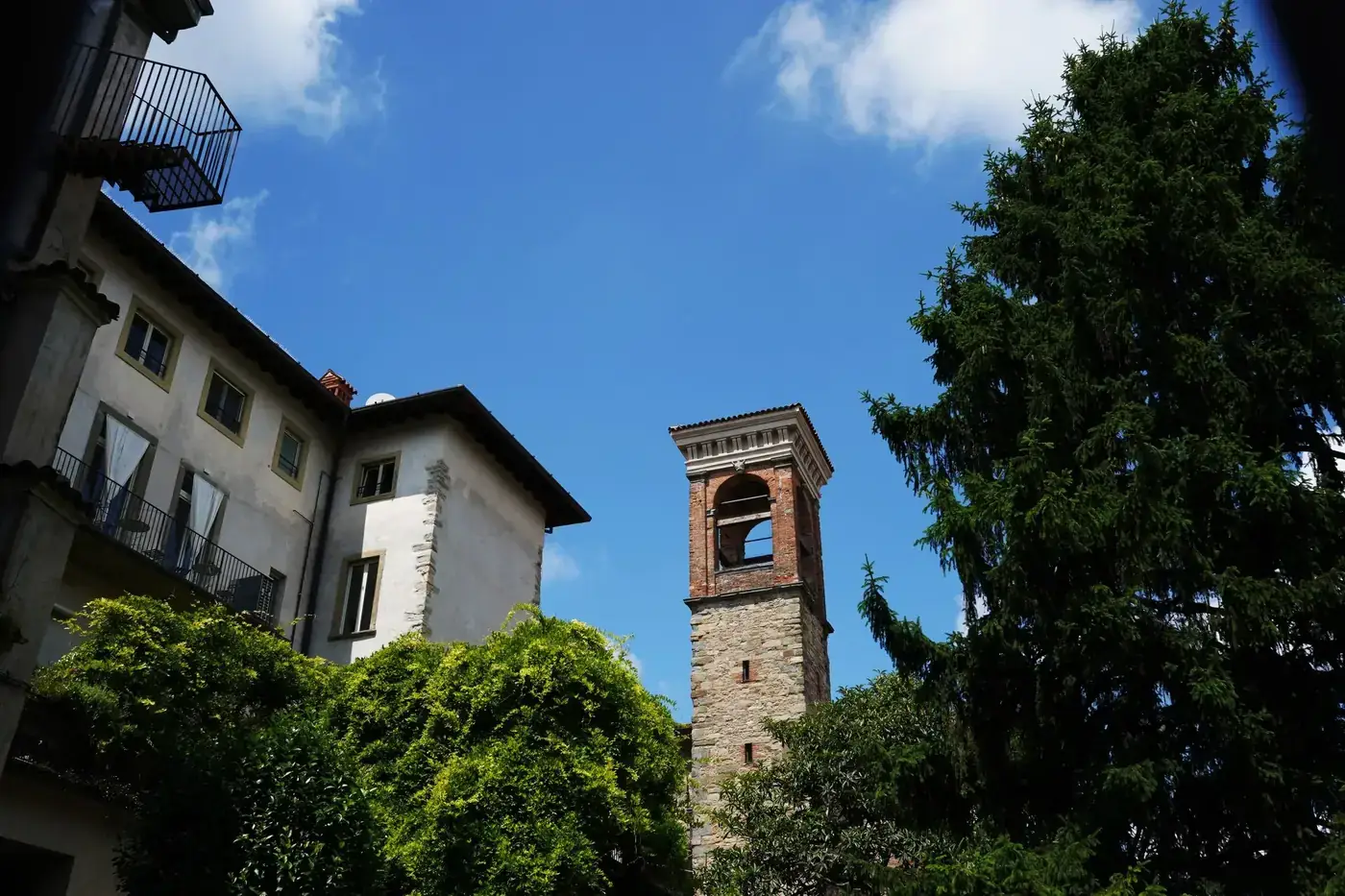 View of a historic bell tower and lush greenery in Bergamo, Lombardy, showcasing Italian architecture.