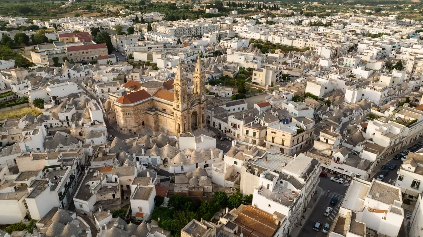 Aerial view of a historic Italian town featuring a prominent church amidst traditional buildings.