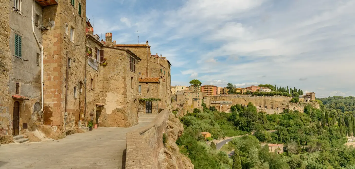 Picturesque view of a historic Tuscan village with ancient stone buildings and lush greenery.