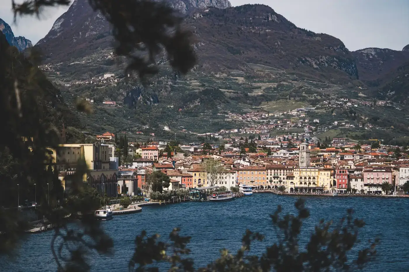 Picturesque view of Riva del Garda against mountainous backdrop with Lake Garda in the foreground.