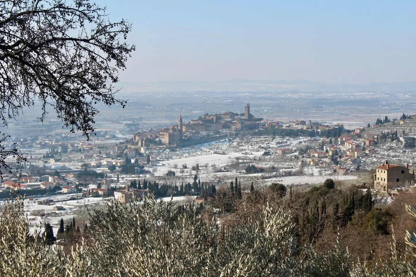 Breathtaking aerial view of Castiglion Fiorentino under a light snowfall, showcasing historic architecture and winter la