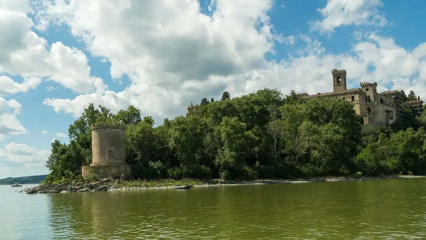 Explore the serene landscape of Umbria with its historic castle by the river under a clear summer sky.