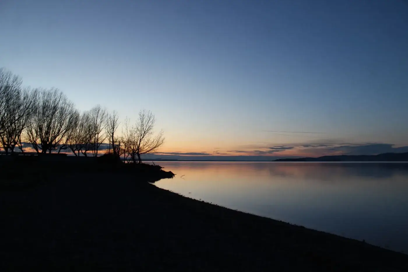 Scenic sunset at Lake Trasimeno with serene water reflections in Umbria, Italy.