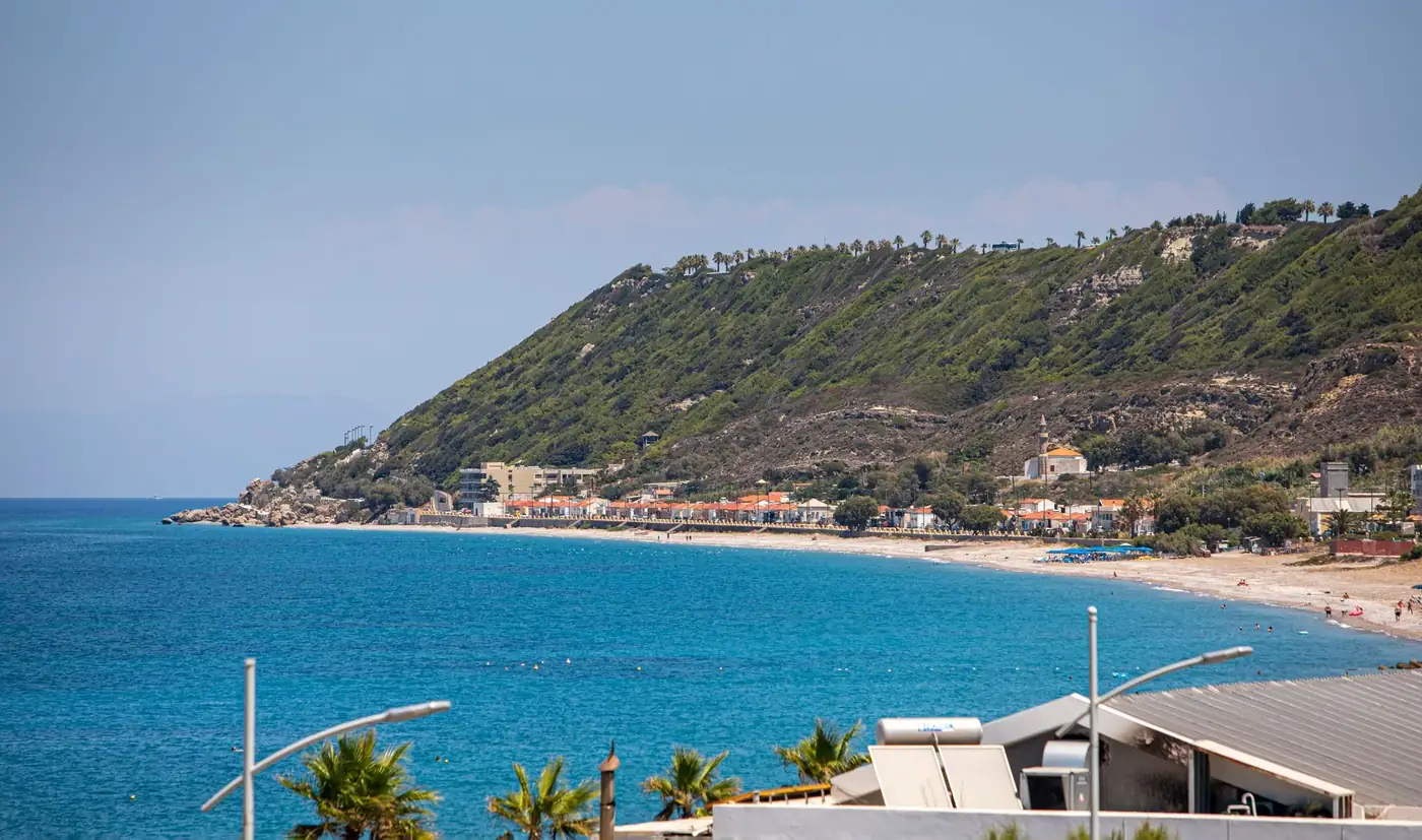 Breathtaking view of a coastal town alongside a turquoise sea and lush hillside.