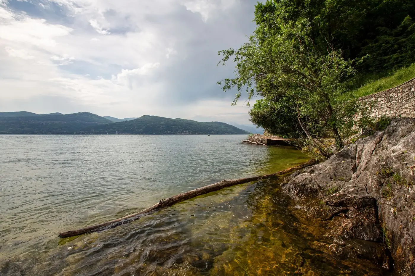 Serene lakeside landscape at Ispra in Lombardia, Italy with lush greenery and clear waters.