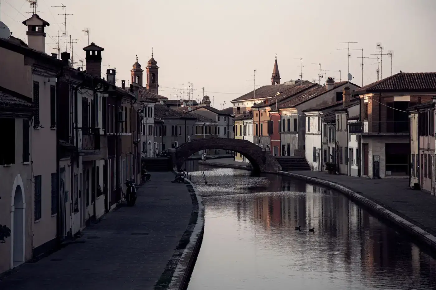 Charming canal scene in Comacchio, Italy featuring historical architecture and a serene water reflection.