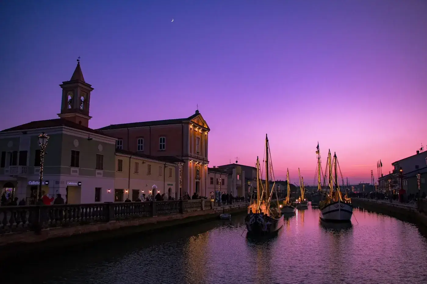 Picturesque canal at sunset with vibrant boats and historic buildings. Serene twilight scene.