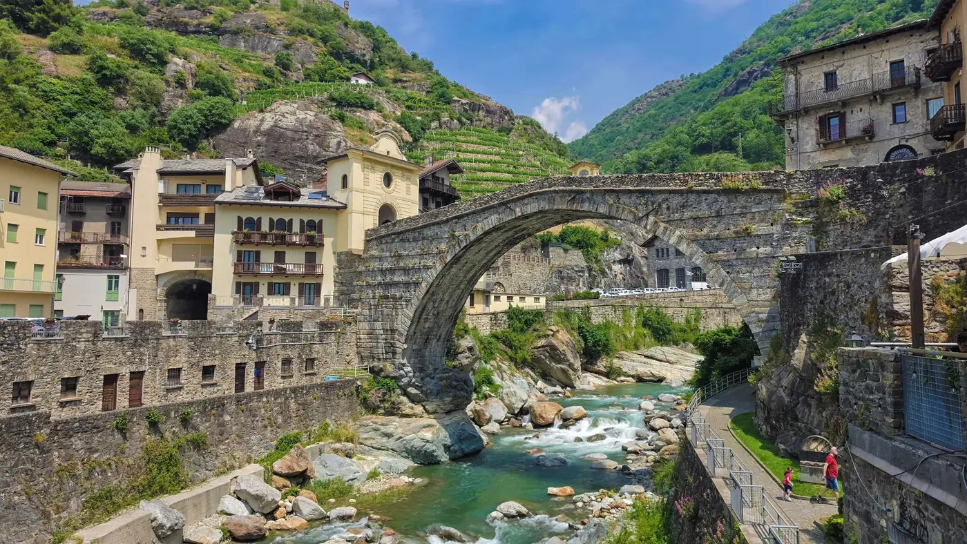 Picturesque view of the Roman bridge and surrounding village in Pont-Saint-Martin, Italy.