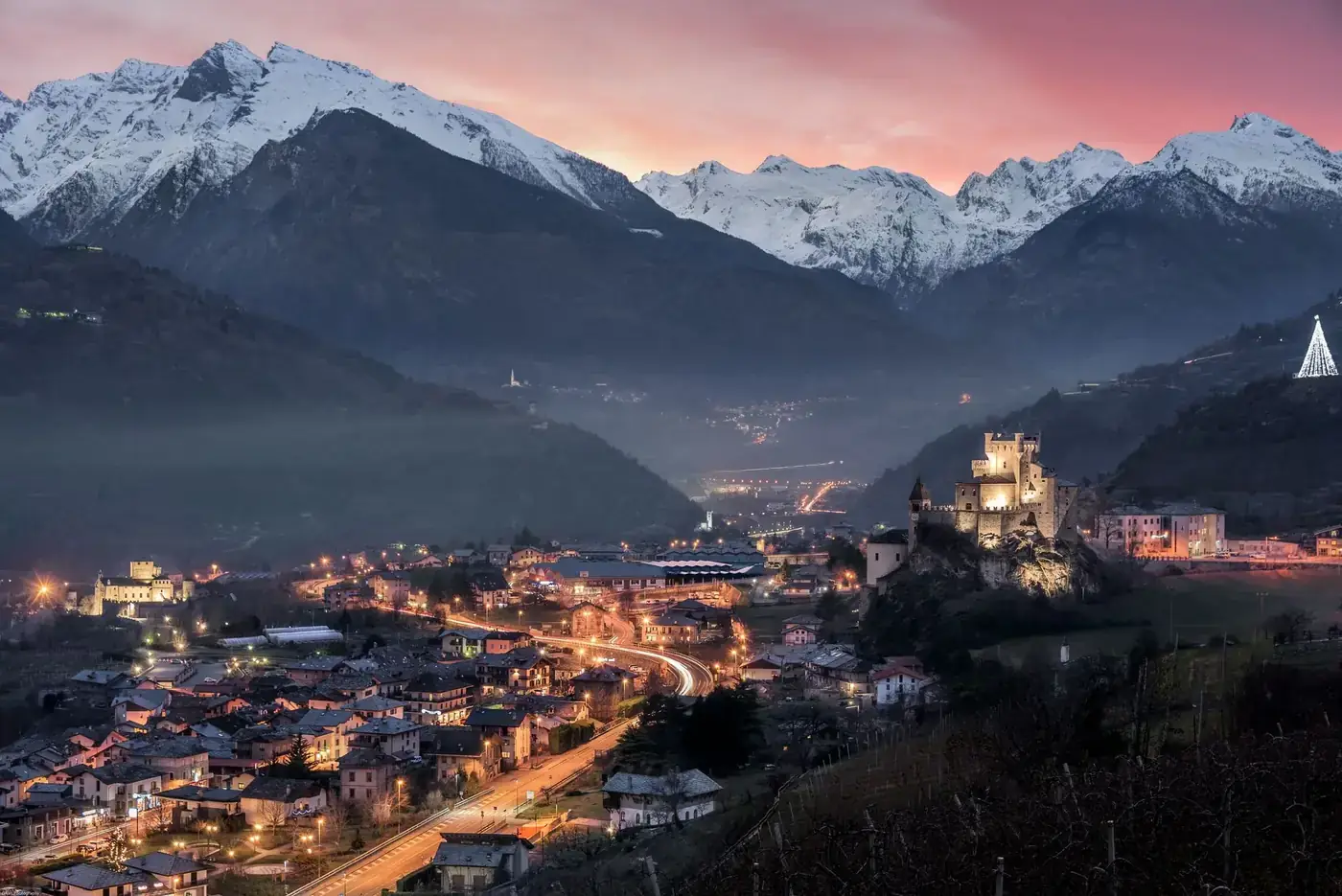 Enchanting evening view of Saint-Pierre with snow-capped mountains and a lit castle.