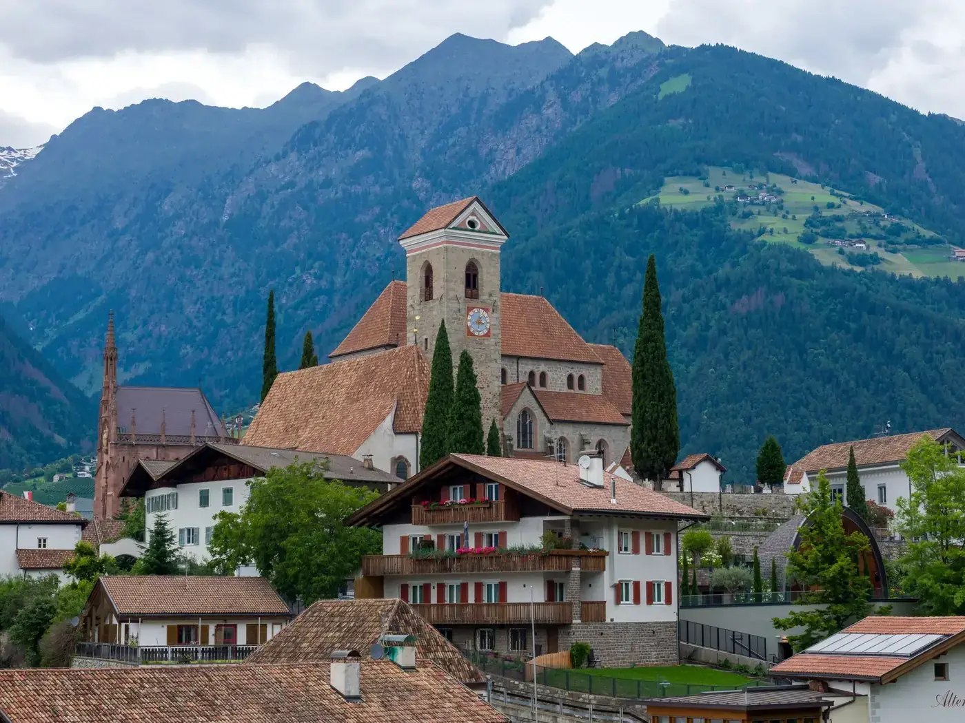 Scenic view of a village church in Dorf Tirol, surrounded by mountains in South Tyrol during summer.