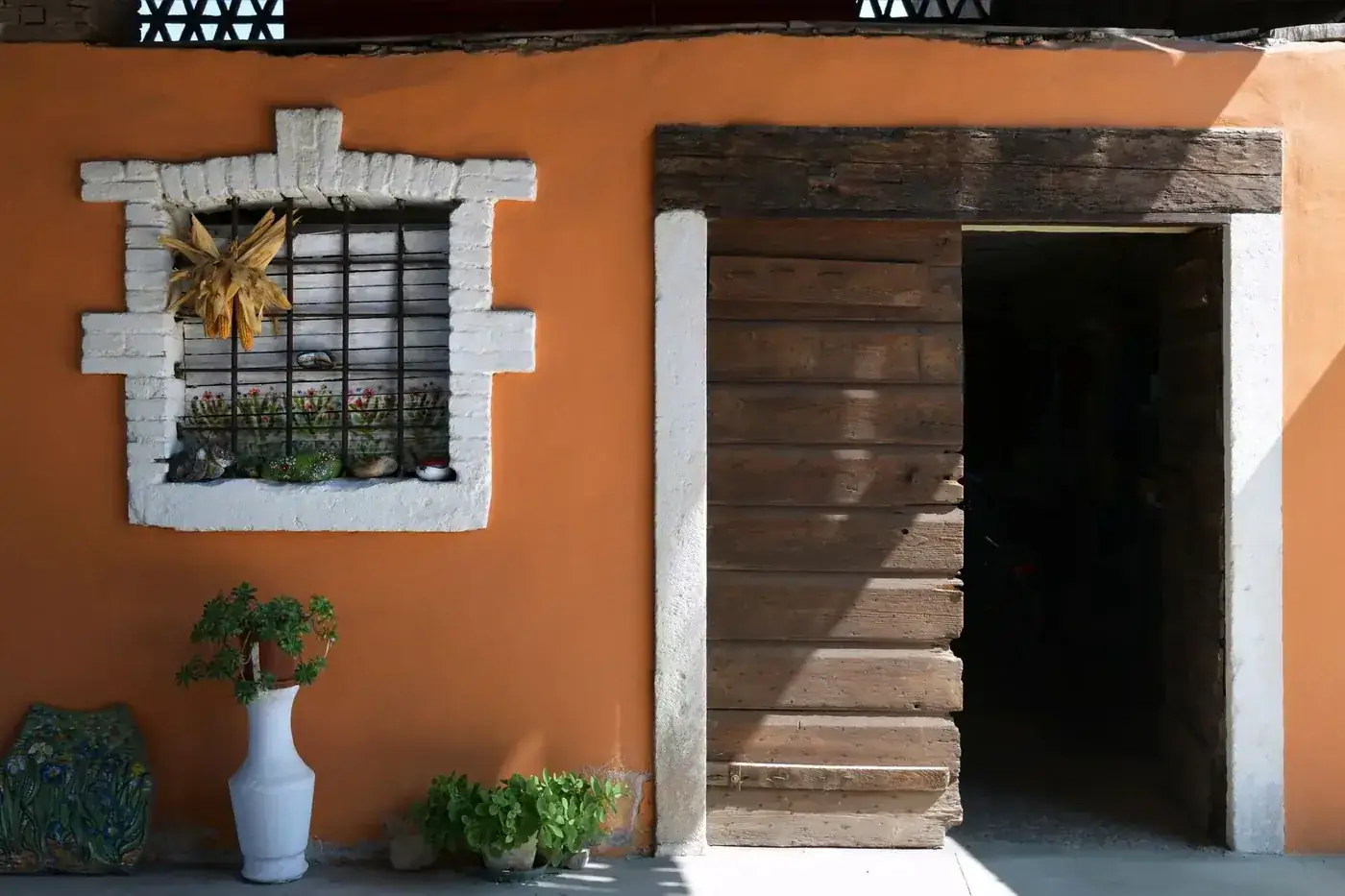 Rustic wooden door and vibrant window display in Rizza, Veneto, Italy.