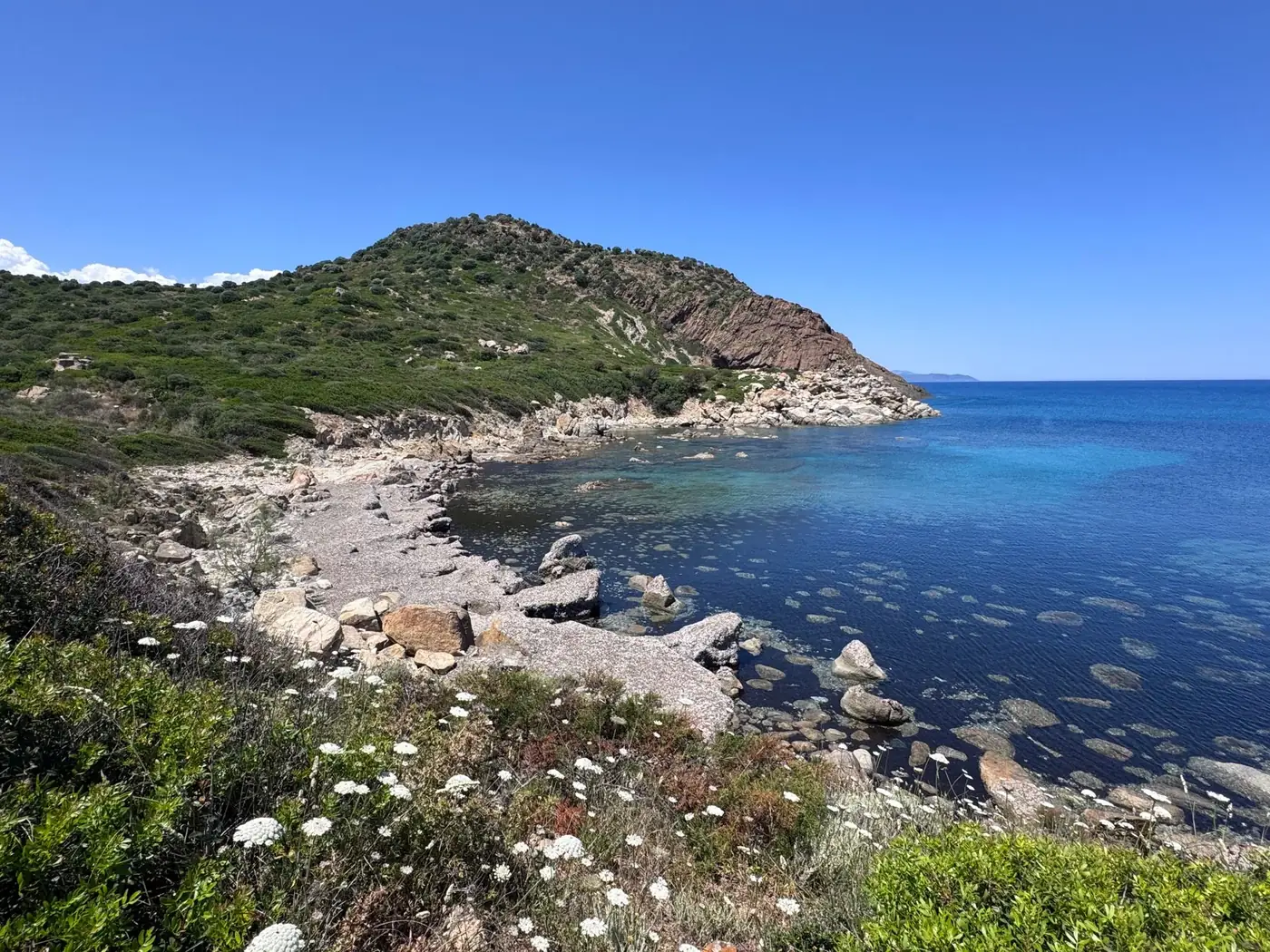 Beautiful view of rocky coastline with clear blue water in Sardinia, Italy, under a bright summer sky.