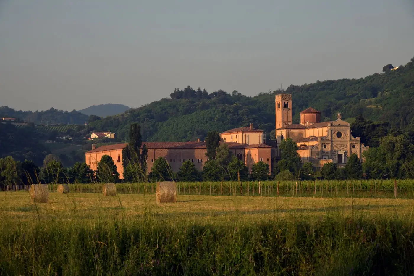Charming abbey nestled in Abano Terme's lush vineyards during sunset.