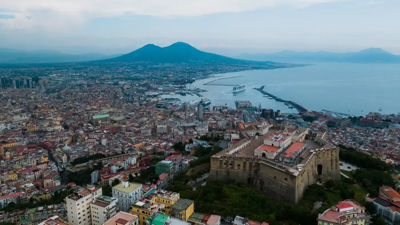 A stunning aerial view of Naples featuring the Castel Sant'Elmo and Mount Vesuvius.