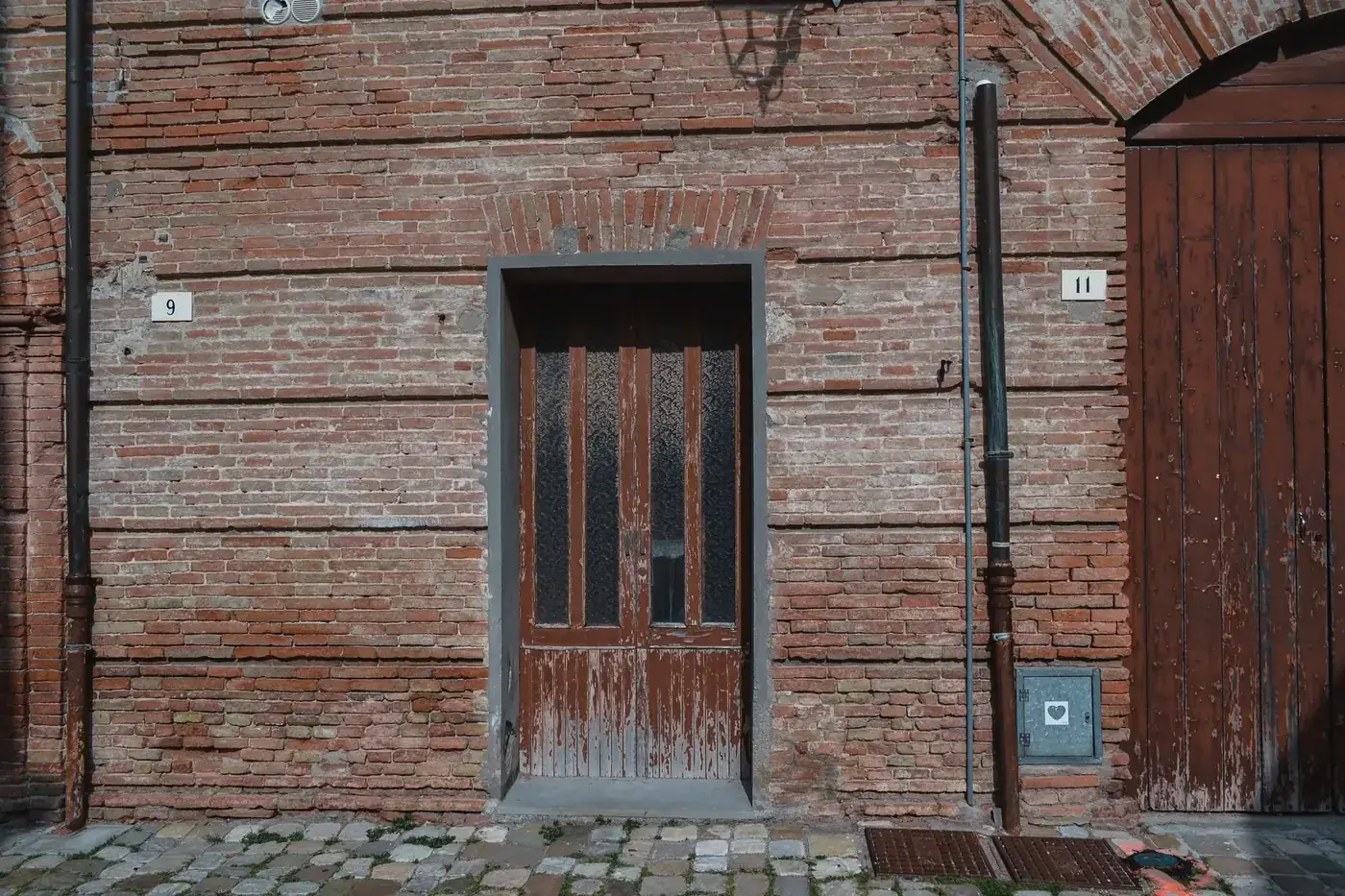 Aged brick wall with vintage wooden door in Santarcangelo di Romagna, Italy.