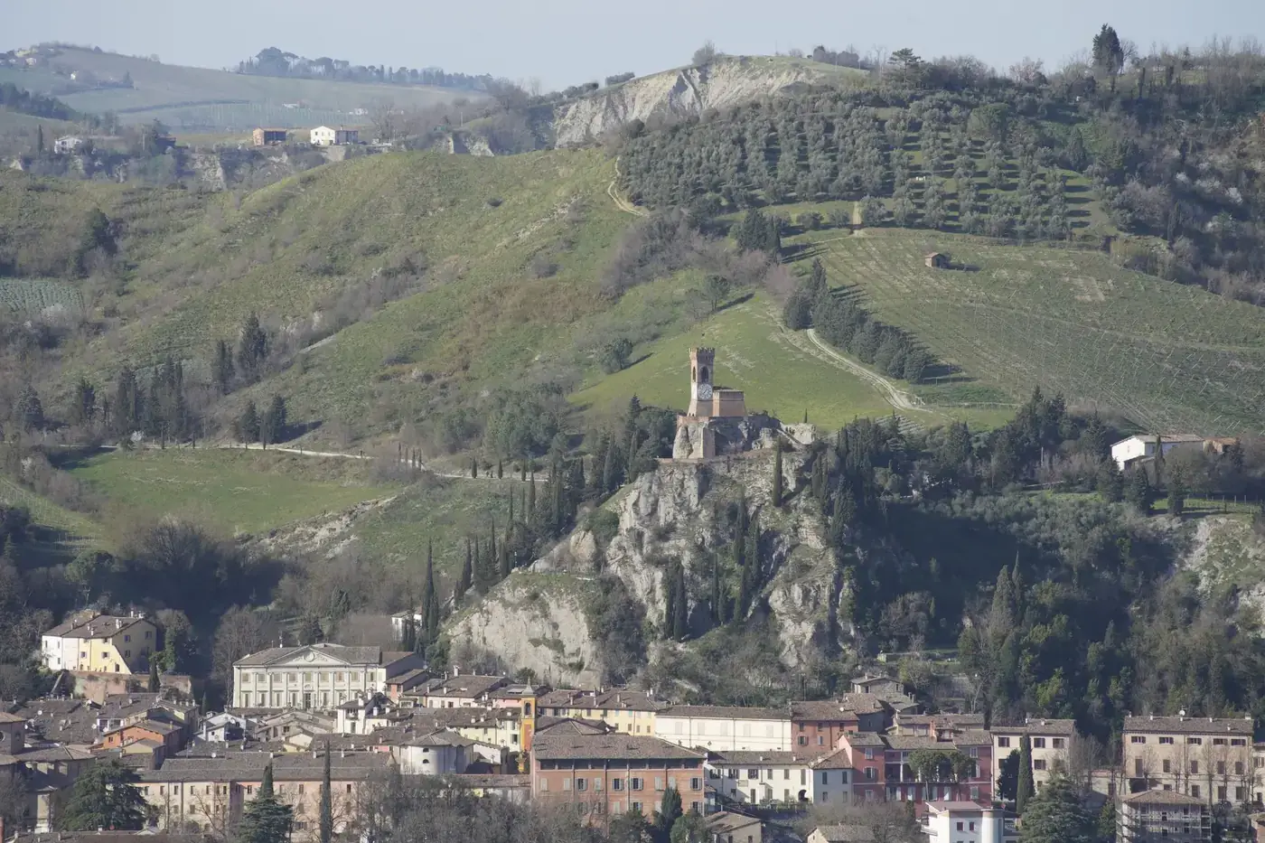 Scenic view of Brisighella with iconic clock tower and lush hills in Emilia-Romagna, Italy.