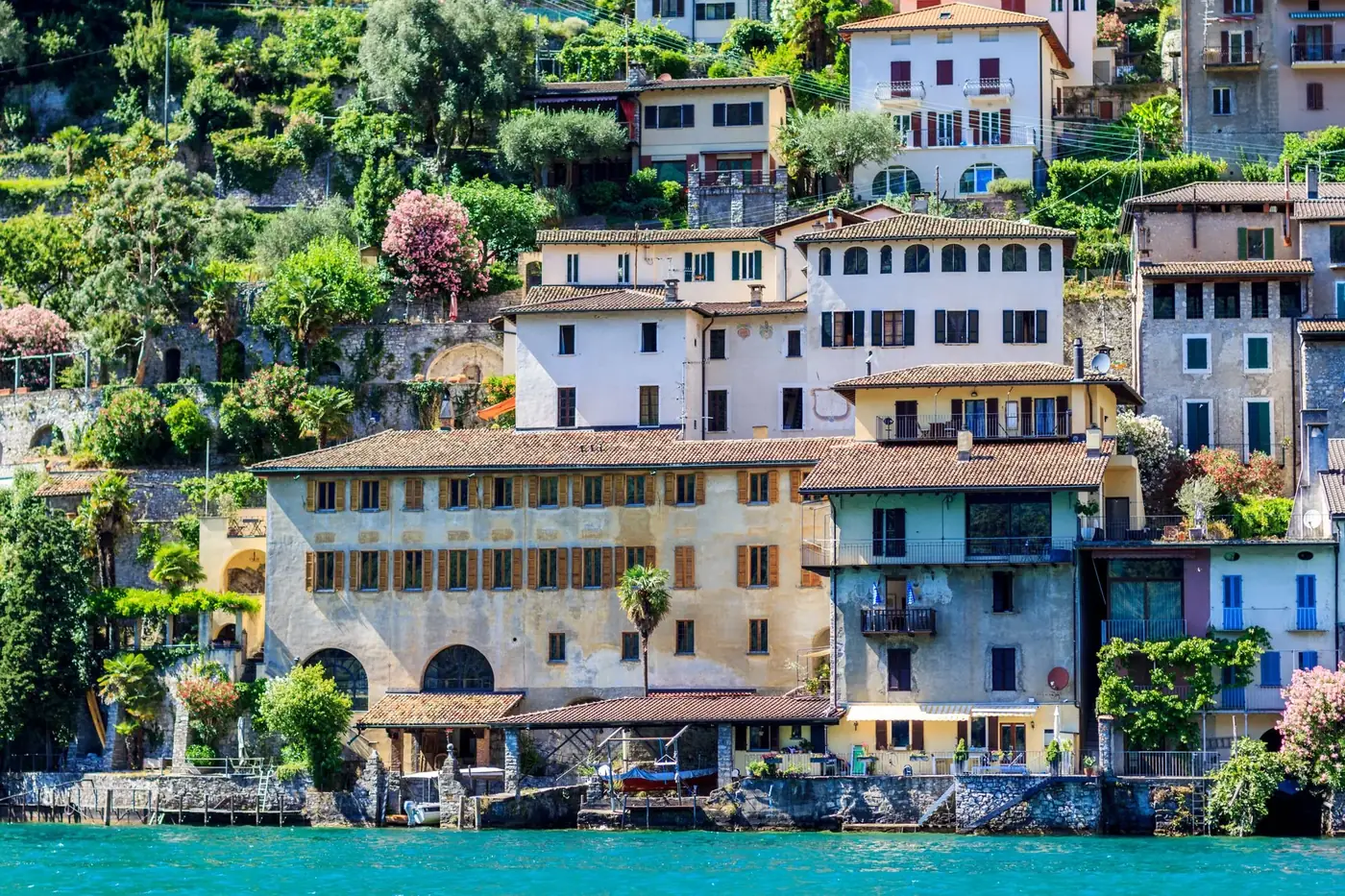 Scenic view of hillside Italian village, colorful houses by Lake Lugano.