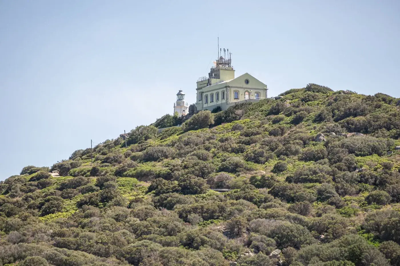 Scenic view of Capo Carbonara Lighthouse atop a lush hill in Villasimius, Sardinia.