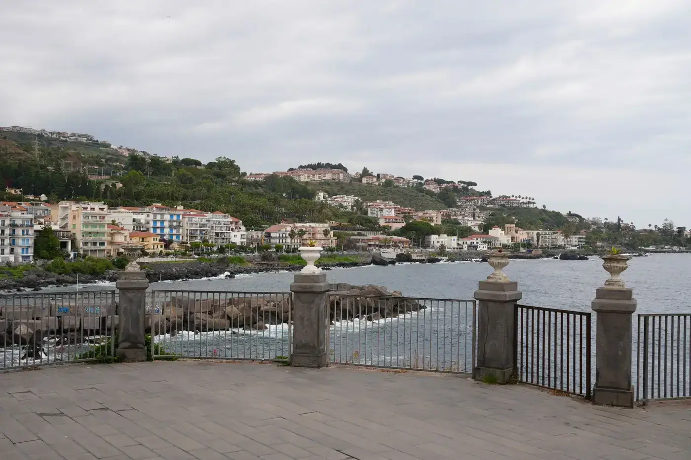 Beautiful coastal view of Acireale with sea and buildings on a cloudy day.
