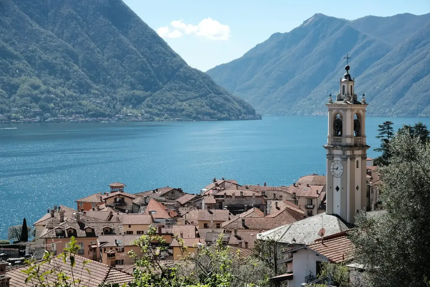Stunning view of Lake Como from the village with a prominent bell tower against mountainous backdrop.
