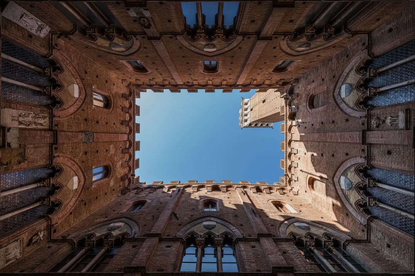 Stunning upward view of the Palazzo Pubblico courtyard in Siena, Italy.