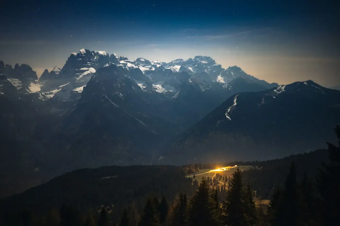 Stunning astrophotography showcasing the Milky Way over snow-capped Italian Alps at night.