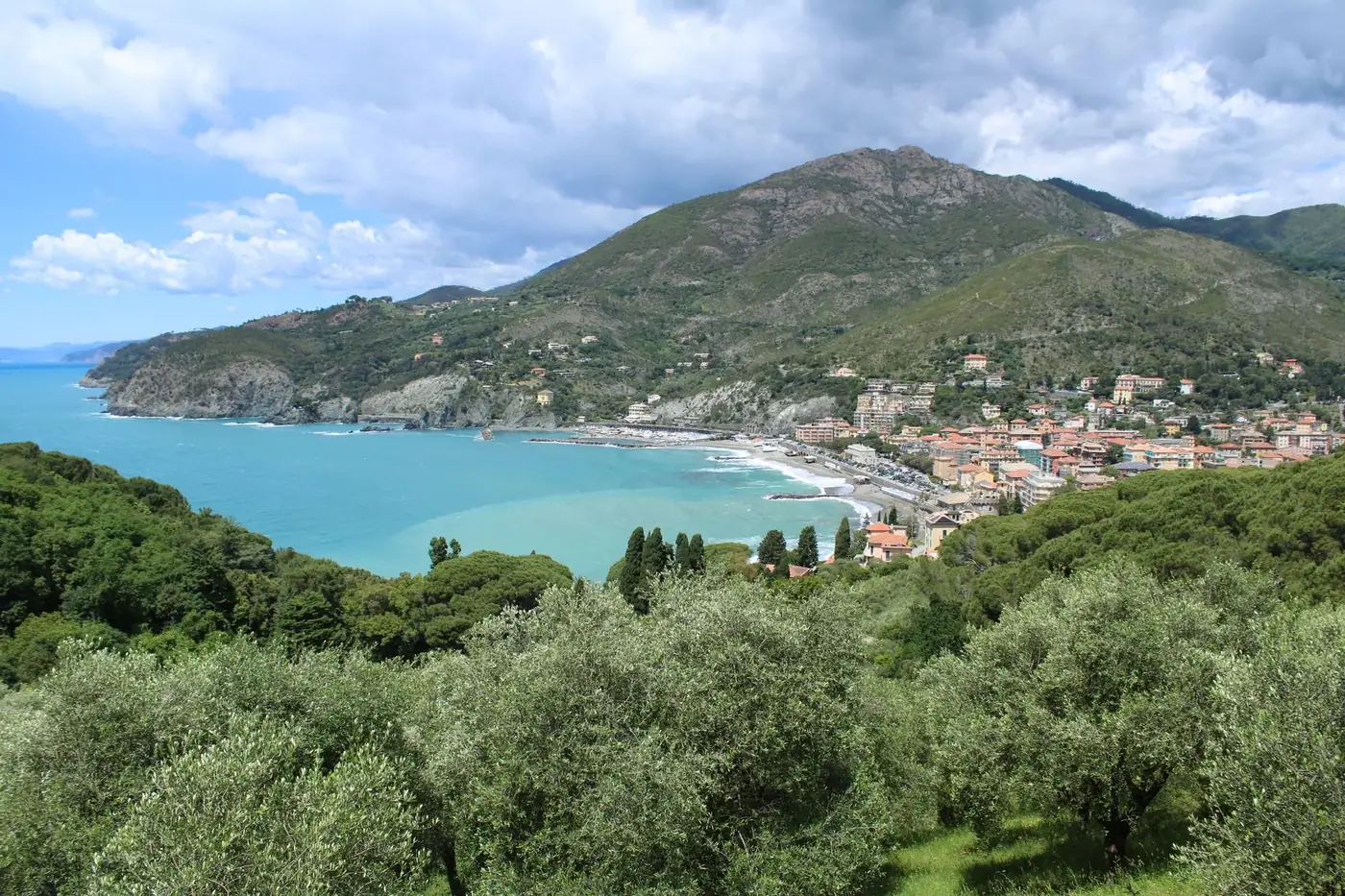 A picturesque coastal view of Liguria, Italy, with mountains and turquoise sea.