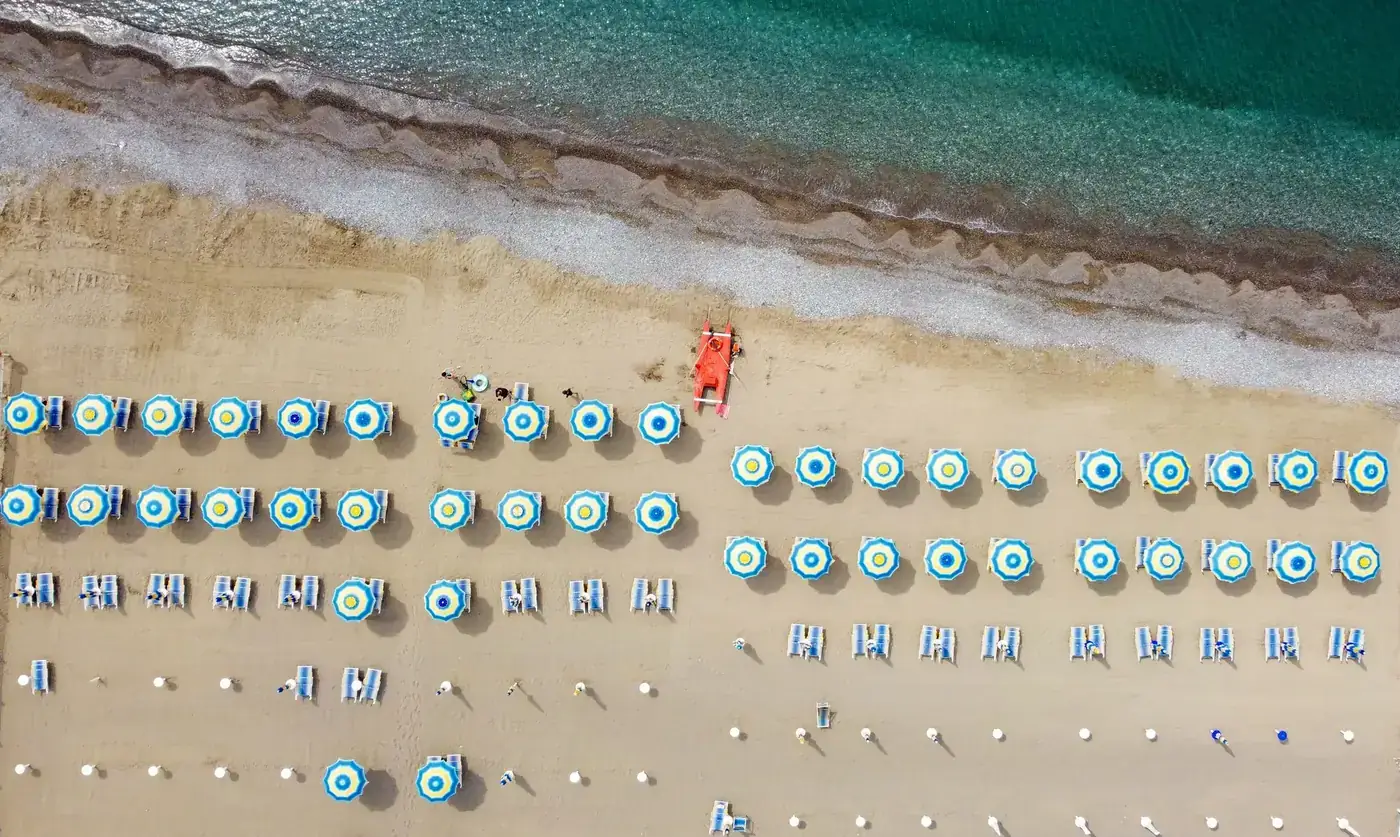 Aerial view of colorful beach umbrellas and loungers on Santa Marina beach, Italy.