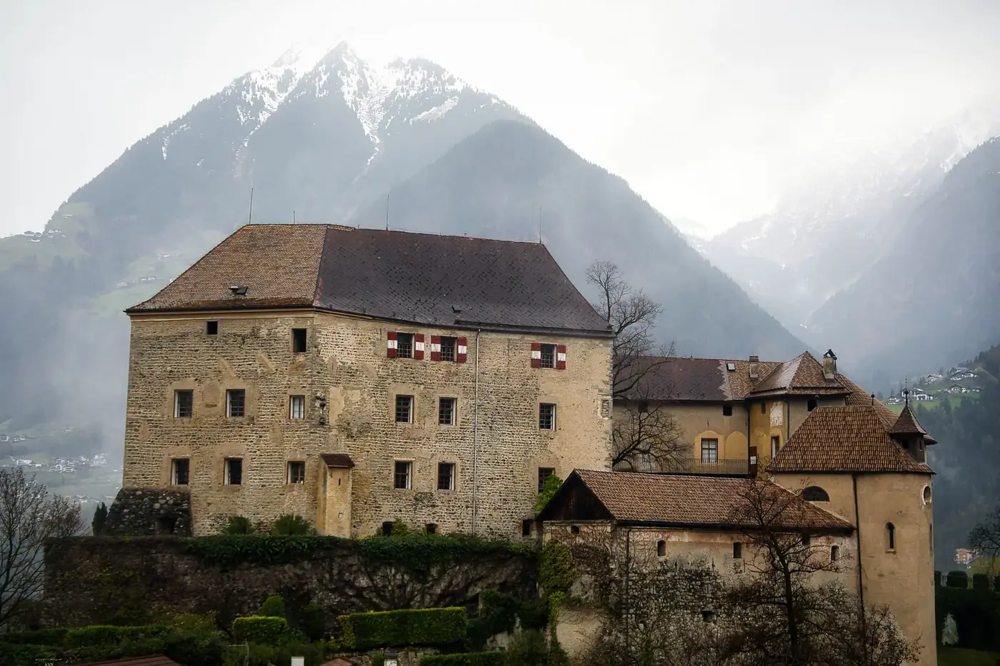 A picturesque castle in Schenna, Italy, set against majestic alpine mountains.