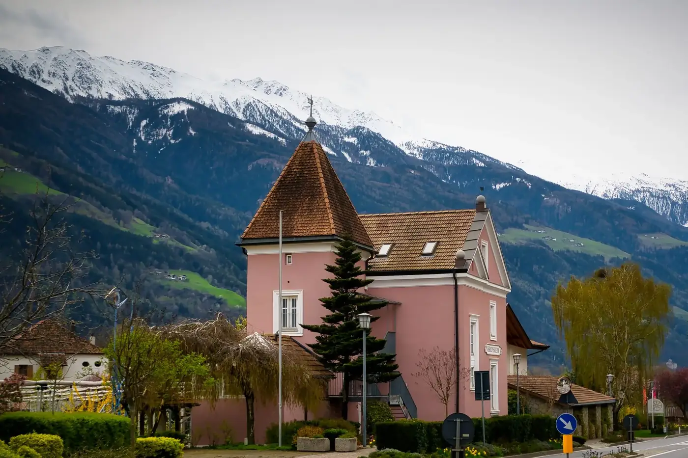 Picturesque pink house in Rabland, Italy, with snow-capped mountain vista.