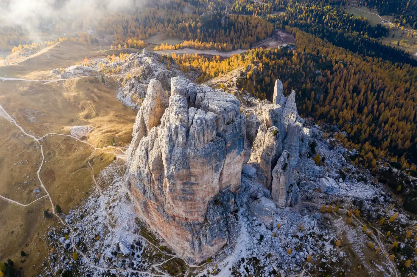 Stunning aerial view of Dolomite rock formations with autumn foliage and scenic trails.
