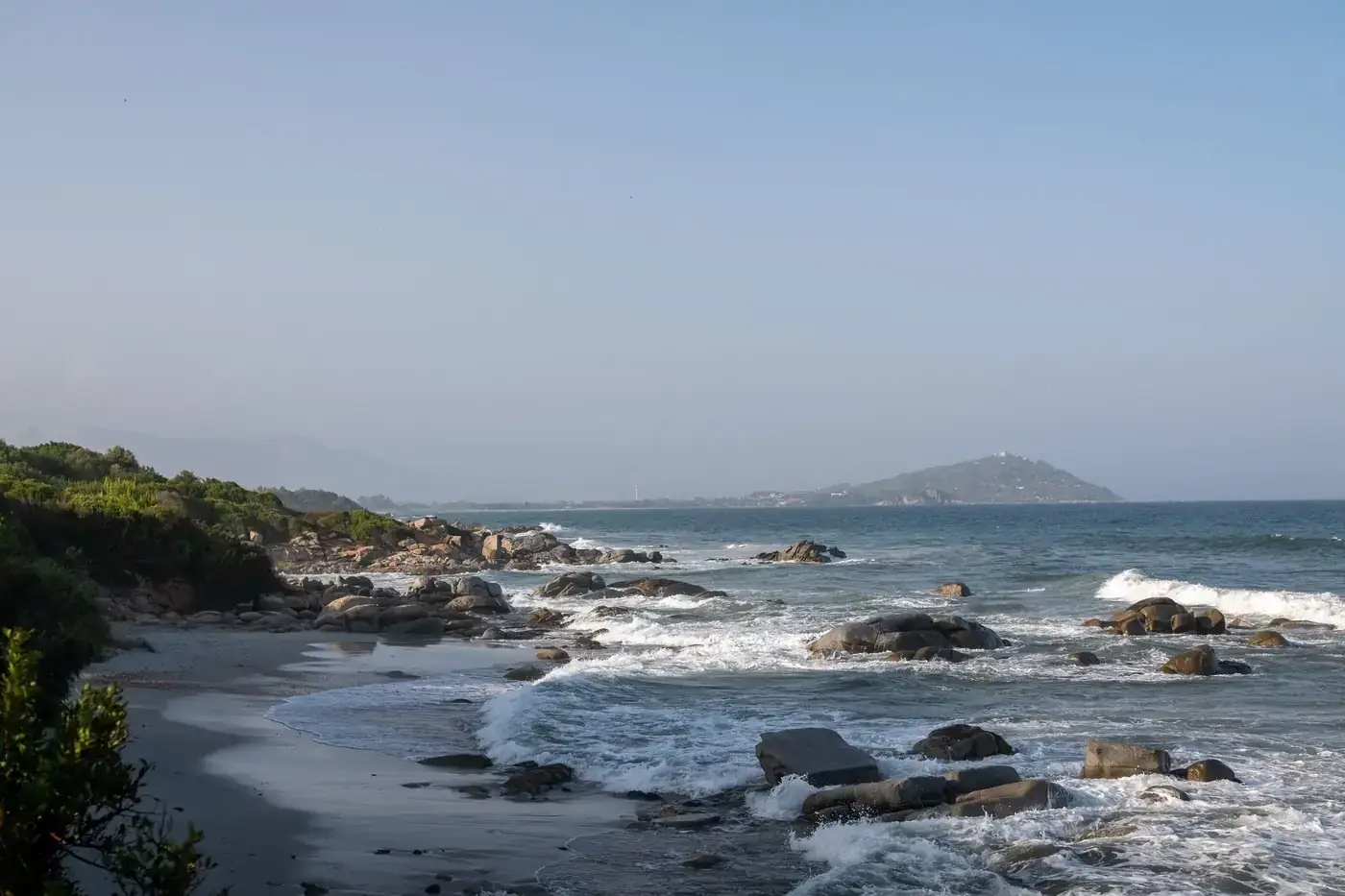 Peaceful coastal scene of a rocky beach with gentle waves in Sardinia, Italy.