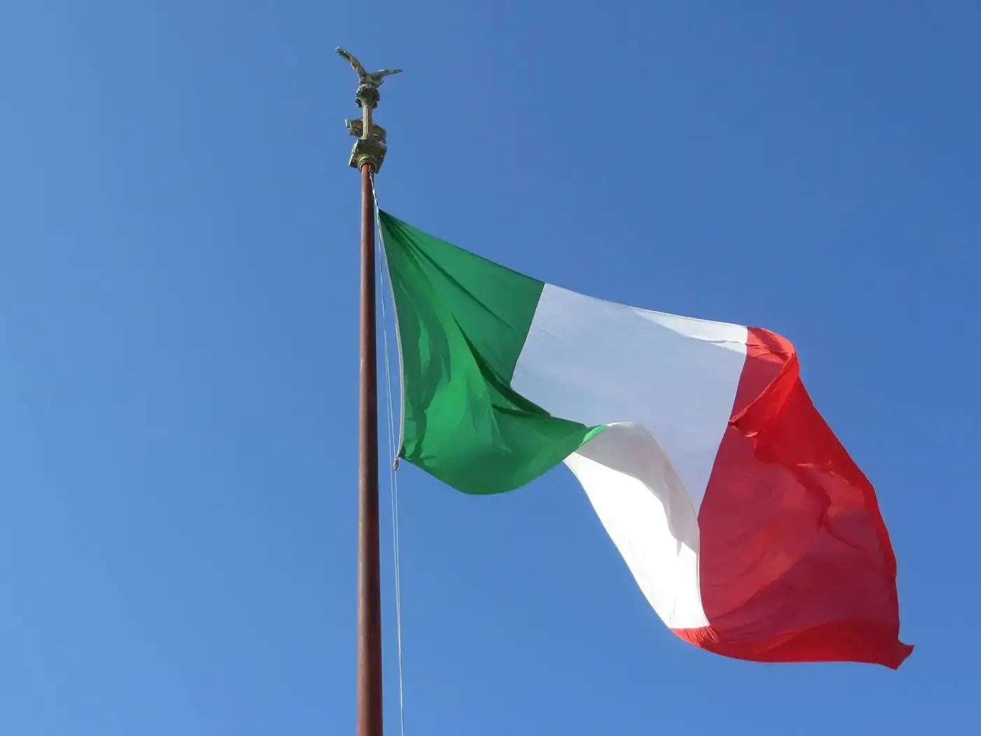 The Italian flag waves proudly under a clear blue sky in Rome, symbolizing national pride and patriotism.