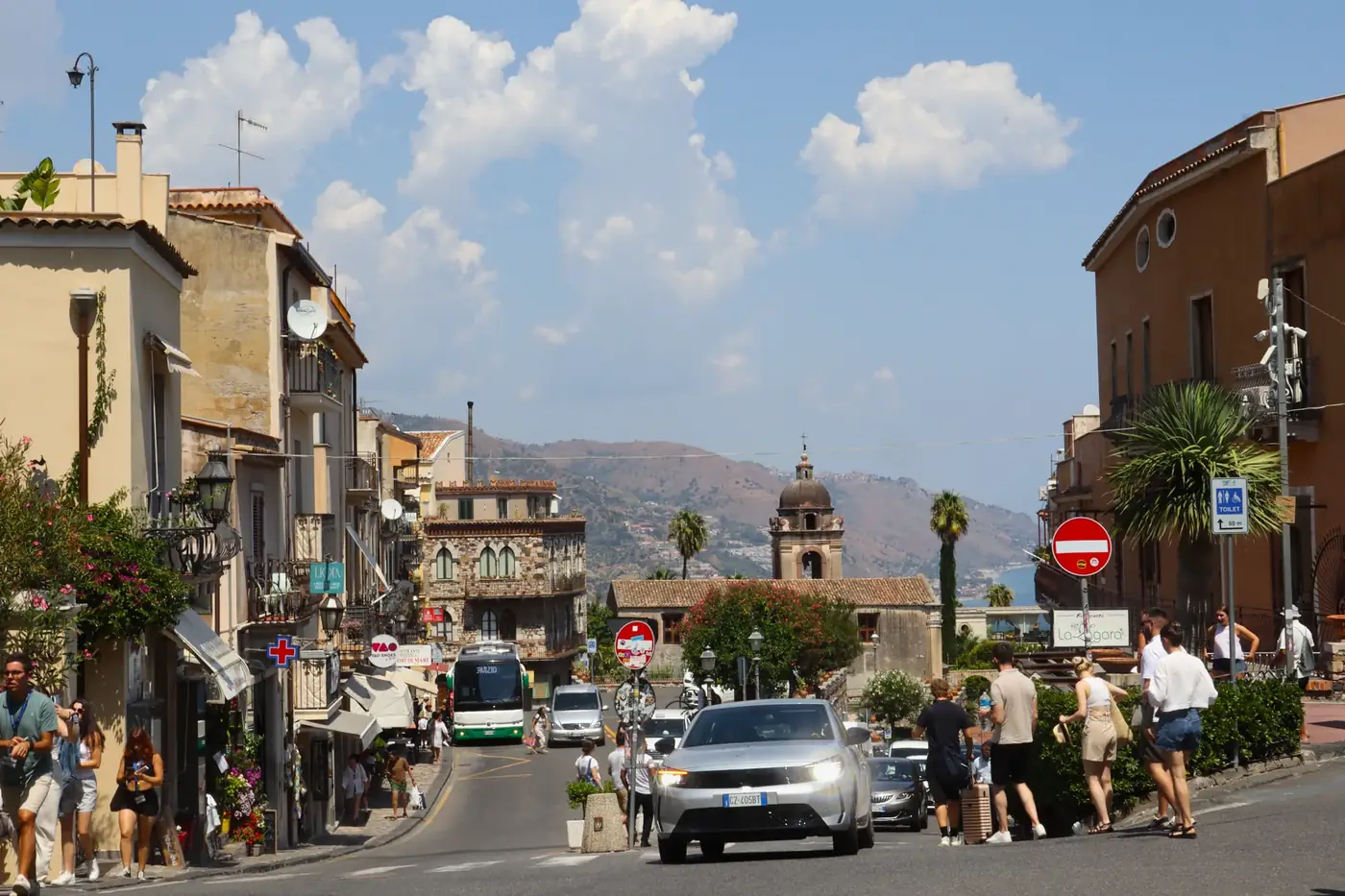 Tourists enjoy a sunny day exploring the vibrant streets of Taormina, Sicily, Italy.