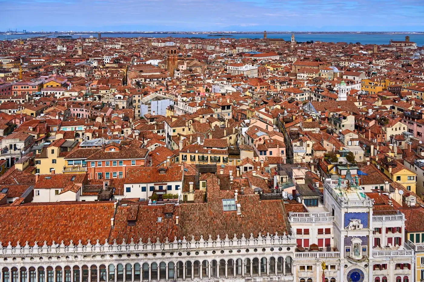 Stunning aerial view of Venice showcasing red-tiled rooftops and historic architecture against a blue sky.
