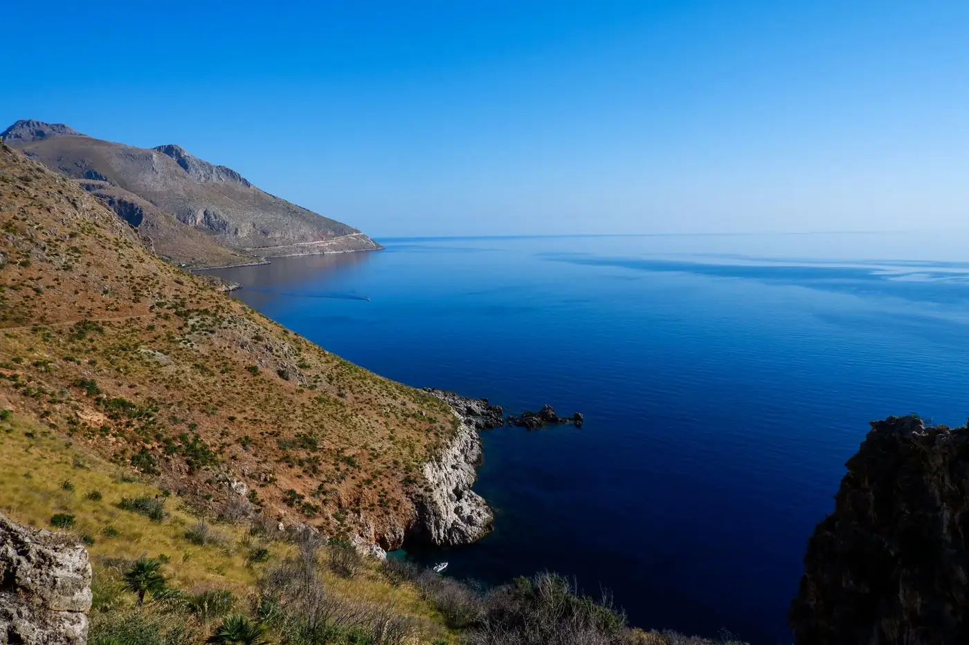 Breathtaking view of Scopello's coastline in Sicily featuring clear blue sea and rugged mountains.