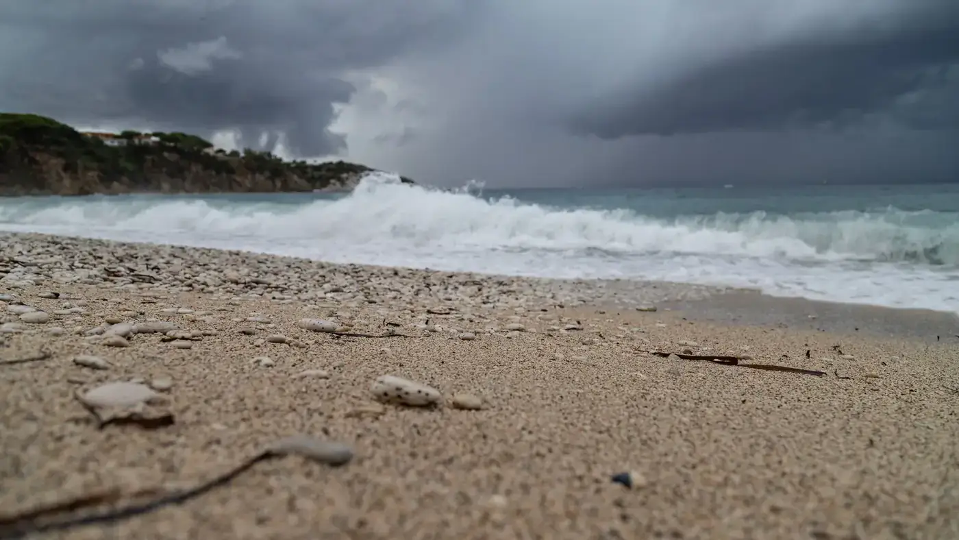 Moody beach scene with crashing waves and storm clouds in Portoferraio, Italy.