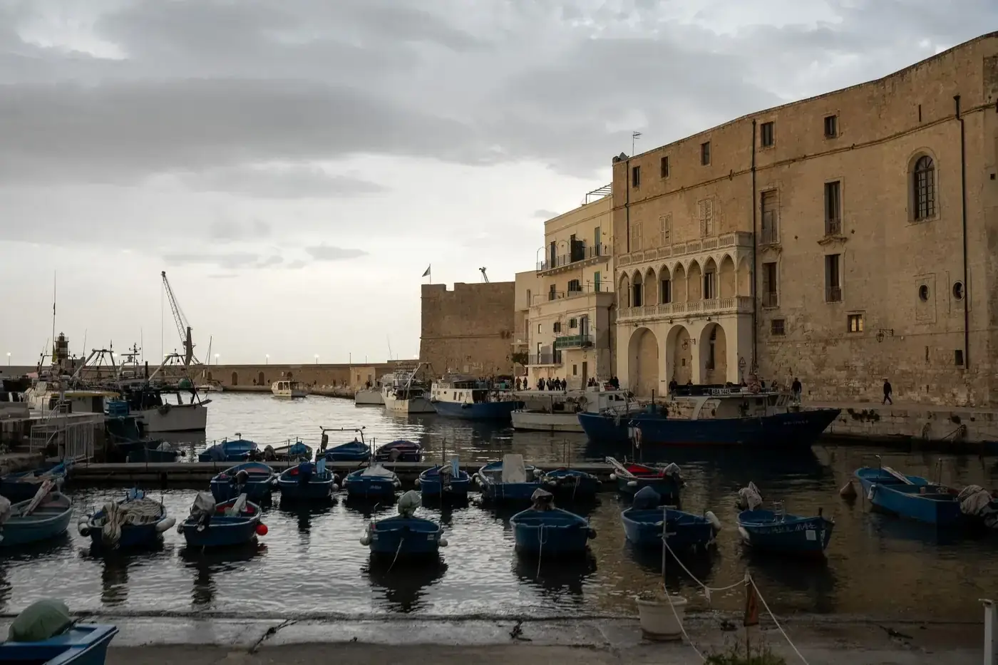 Discover the serene beauty of Monopoli's historic port in Apulia, Italy, captured at dusk with boats and historic archit